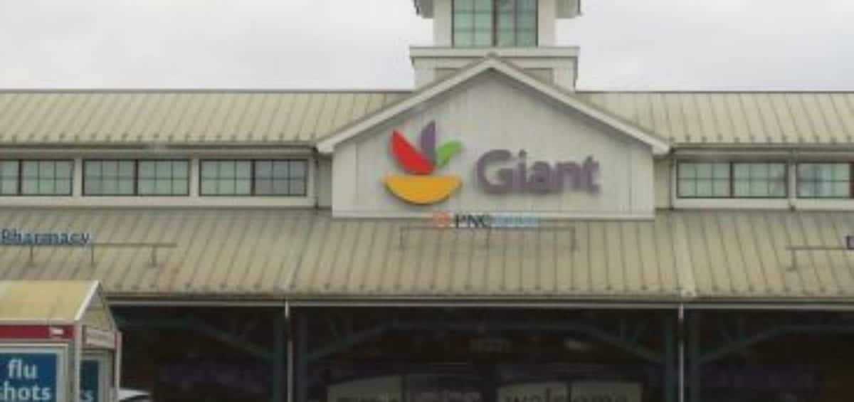 A Giant supermarket with a visible pharmacy sign, parking lot and a few parked cars. It is a cloudy day, and there is a small tower on the roof of the store.