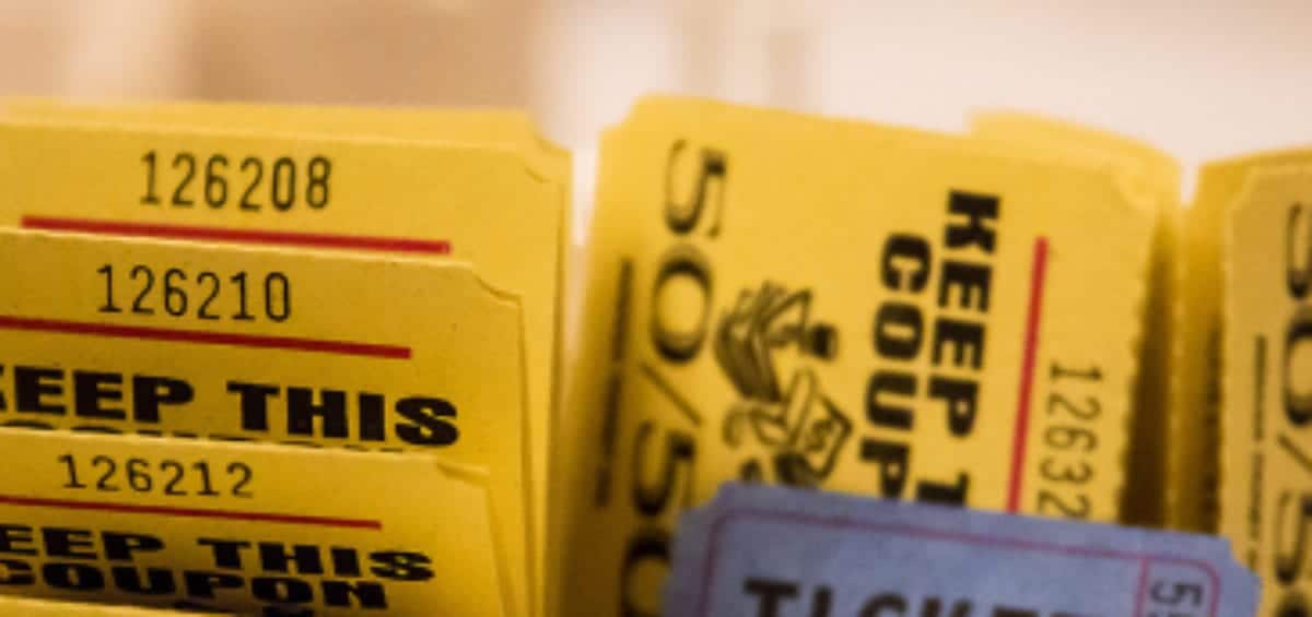 A close-up of a stack of yellow "KEEP THIS COUPON" tickets with one blue "TICKET" showing the number 559086 in the foreground.